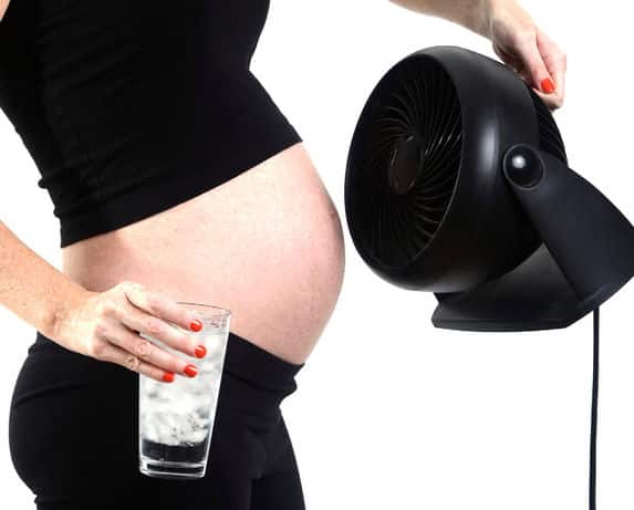Photo - femme enceinte avec ventilateur et verre d'eau glacée